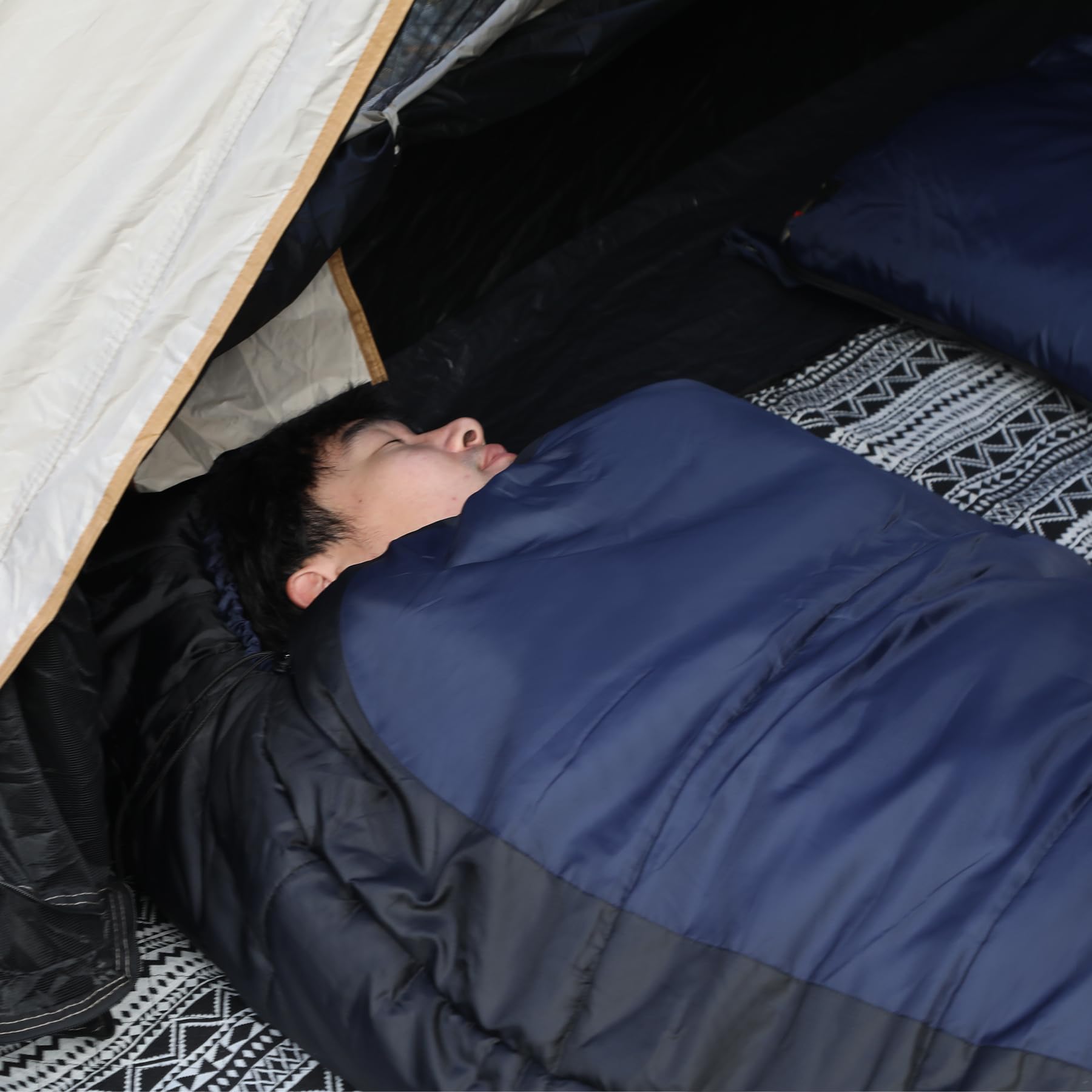 Person sleeping inside a navy mummy sleeping bag in a tent