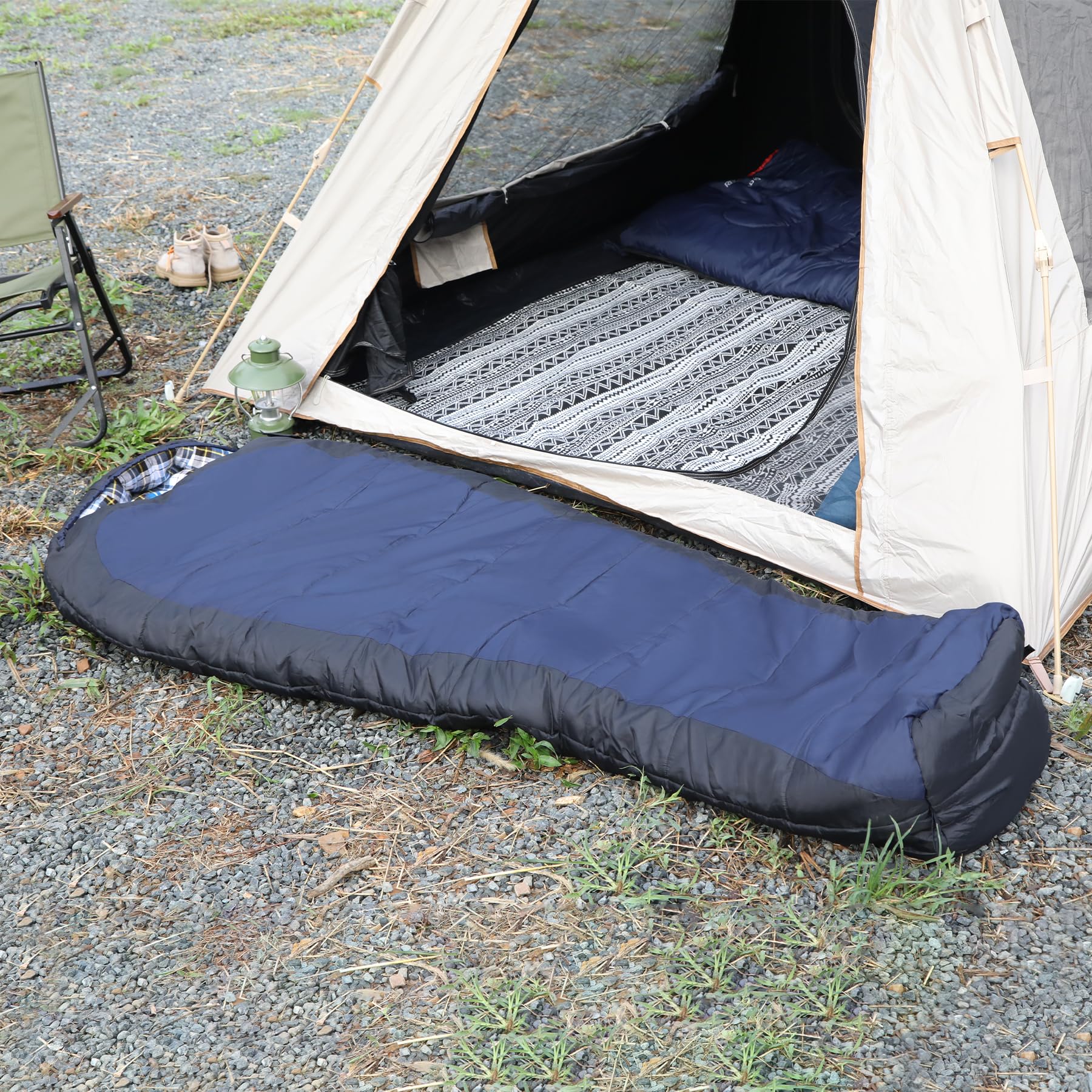 Navy mummy sleeping bag laid out beside a camping tent